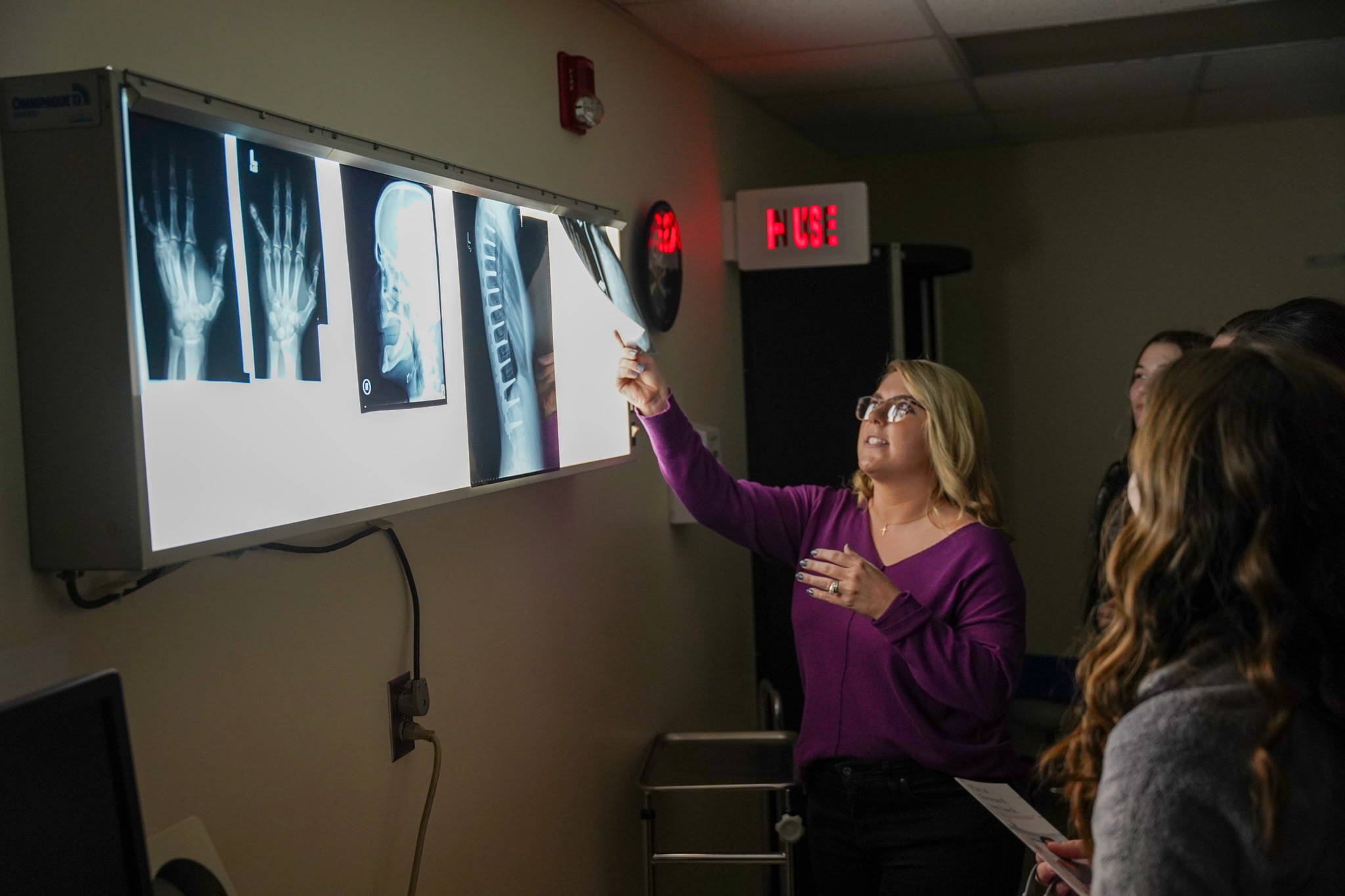 woman teaching other girls while showing an xray on a screen