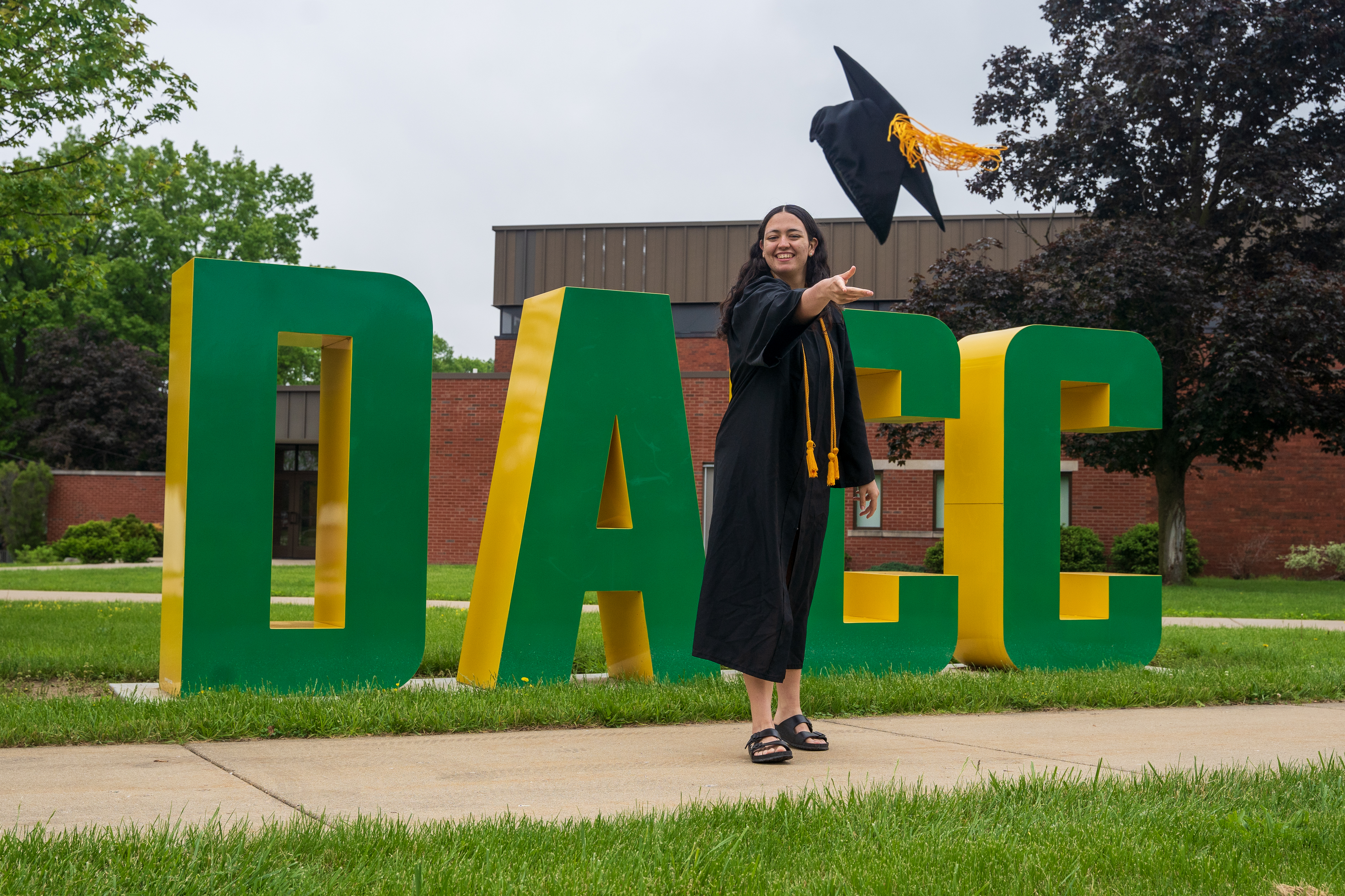 All Star Jaguar throwing a graduation cap in front of the DACC letters